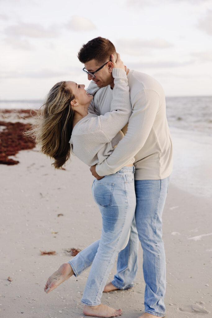 Couple embracing on the beach for engagement photo at Bowditch Point Park in Fort Myers, Florida.