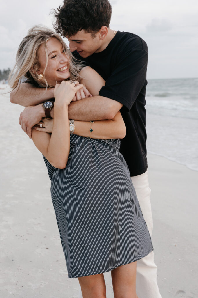 Couple taking engagement photo during surprise engagement on Naples beach in Florida. 