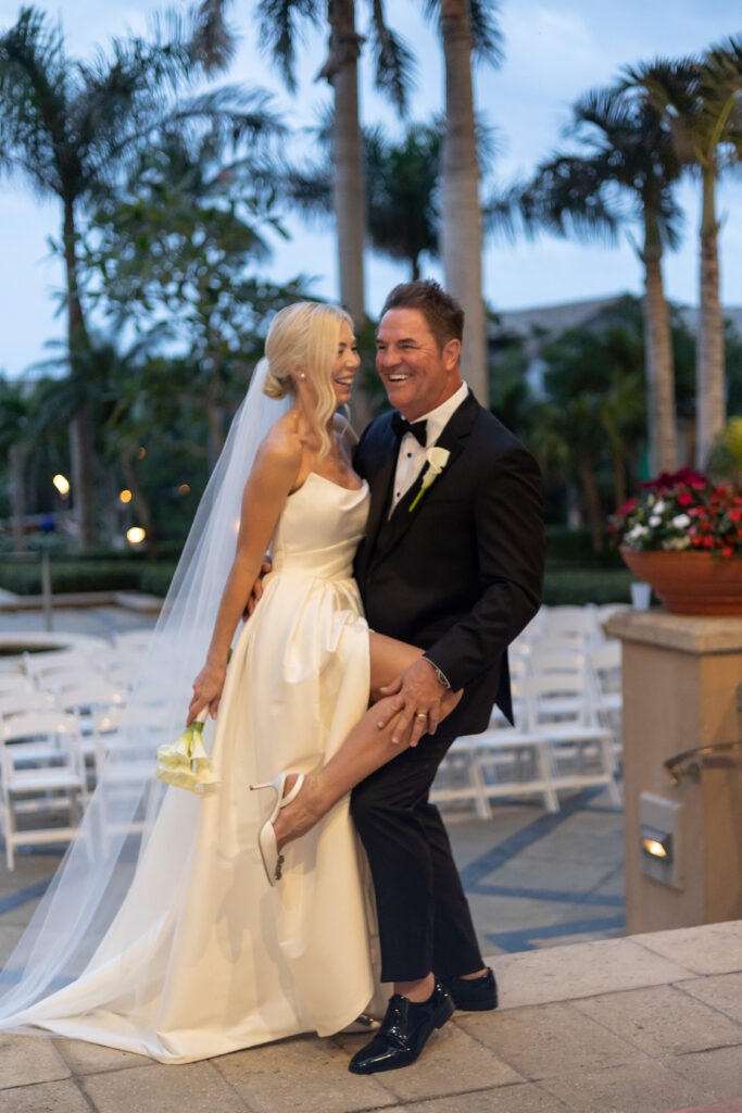 Bride and groom posing happily for bridal portraits during sunset at their wedding at The Ritz-Carlton Resort in Naples, Florida. 