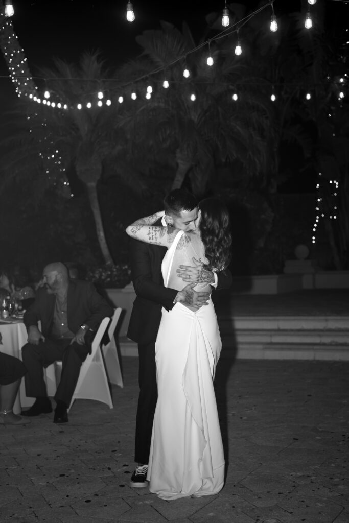 Bride and groom embrace closely during their first dance at their wedding reception at The Club at the Strand in Naples, Florida. 